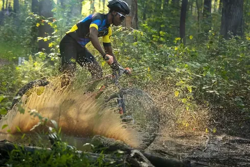 Mountain bike rider rides through puddle
